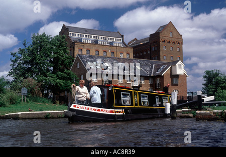 Three people aboard narrowboat working through Coxes Lock on River Wey Navigation, Addlestone, Surrey, England Stock Photo