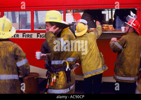 Firefighters / Firemen talking while taking a Coffee Break after fighting a Fire Stock Photo