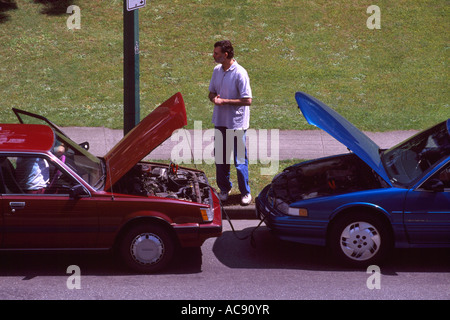 Car Breakdown Trouble - Cars using Jumper Cables to jump start and boost a Broken Down Stalled Vehicle with Dead Battery Stock Photo