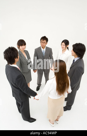 Business people standing in circle holding hands Stock Photo