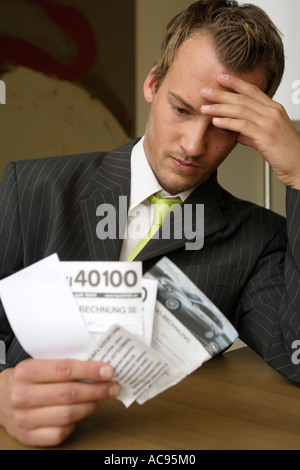 young man holding contemplatively bills in his hand Stock Photo