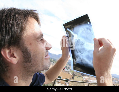 young man watching sun eclipse through a roentgenogram showing an artificial ilium, Spain, Majorca, Alcudia Stock Photo