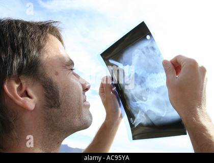 young man watching sun eclipse through a roentgenogram showing an artificial ilium, Spain, Majorca, Alcudia Stock Photo