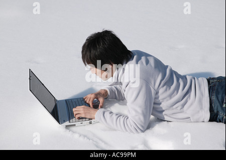 Young man using computer on snow Stock Photo