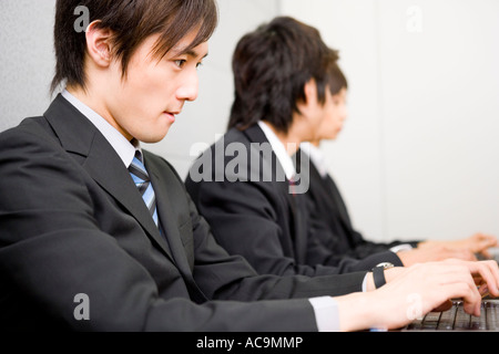 Three young business people using computers Stock Photo