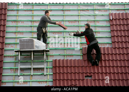 Roof tilers tiling a pointed roof of an apartment house, Essen, North Rhine-Westphalia, Germany Stock Photo