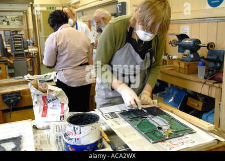 Woman working on stained Glass panel in adult learning class. Model release front person Stock Photo