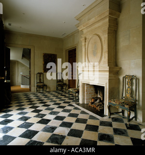 Stone fireplace in empty reception room with chequered floor Stock Photo