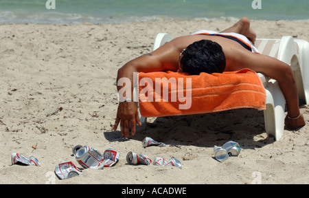Man asleep surrounded by beer cans which are banned on South Beach Art Deco area South Beach Miami Florida USA Stock Photo
