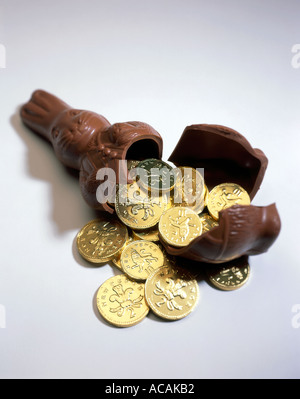 Chocolate Easter Rabbit with coins spilling out of its interior. Studio image on a white background. Stock Photo