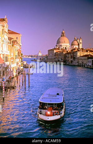 Venice Grand Canal with Vaporetto passenger waterbus in foreground and Basilica di Santa Maria della Salute behind at sunset Venice Italy Stock Photo