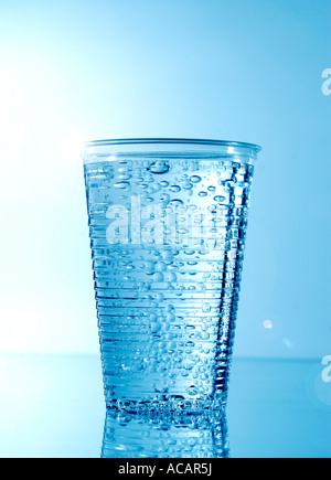 Plastic cup with mineral water, blue background