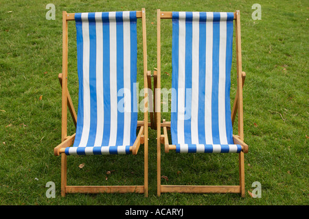 two blue and white stripped empty deckchairs in a park london england uk Stock Photo