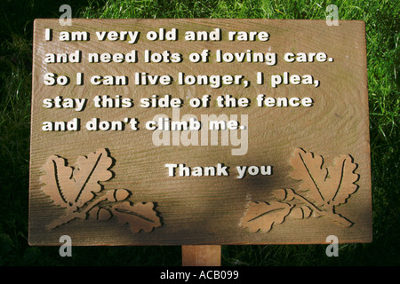 A sign in Sherwood Forest, Nottinghamshire reads: 'I am very old and rare and need lots of loving care.  So I can liver longer, I plea, stay this side of the fence and don't climb on me.  Thank you' Stock Photo