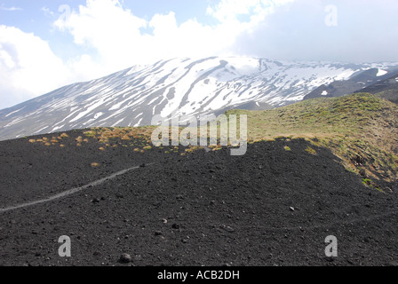 Mount Etna snow covered upper slopes and black lava flows lower, viewed from the North Stock Photo