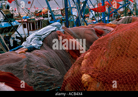 Fisherman sleeping on nets in the harbor of Sidi Ifni Morocco Stock Photo