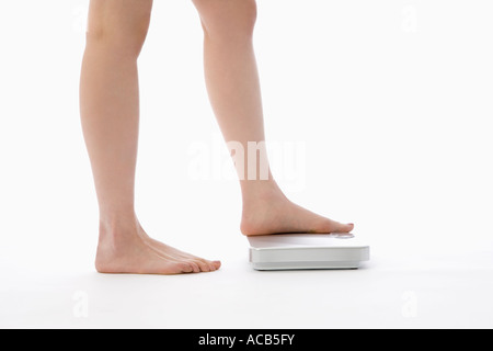 Woman stepping on bathroom scale Stock Photo