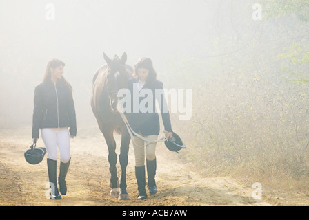 Young woman and a teenage girl walking with a horse Stock Photo