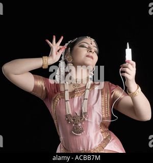 Young woman performing Bharatnatyam and listening to an MP3 player Stock Photo