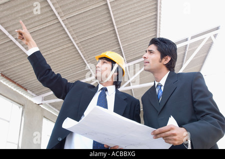 Two architects discussing a blueprint at a construction site Stock Photo