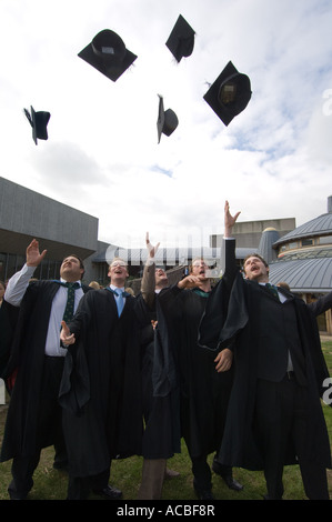 5 five male Aberystwyth University students graduating  - tossing their mortar boards in the air in celebration, Wales UK Stock Photo