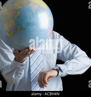Mid section view of a businessman holding a spinning globe and checking the time Stock Photo