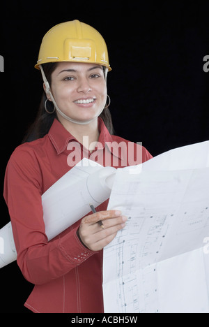 Portrait of a female architect holding a blueprint and smiling Stock Photo