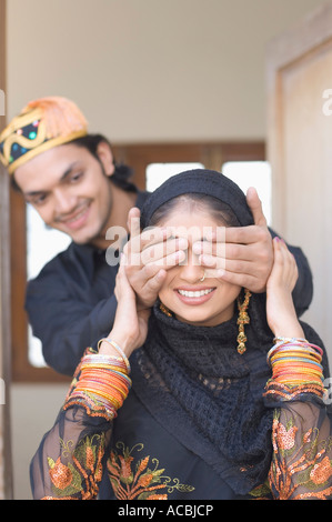 Close-up of a young man covering his wife's eyes from behind Stock Photo