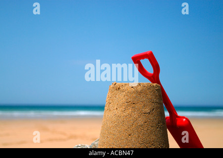 Sandcastle and red spade on rock. Stock Photo