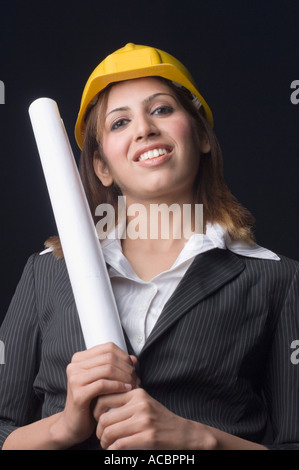 Portrait of a female architect holding a blueprint and smiling Stock Photo