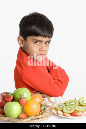 Portrait of a boy looking angry at a breakfast table Stock Photo