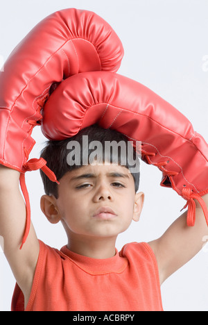 Portrait of a boy wearing boxing gloves and looking sad Stock Photo