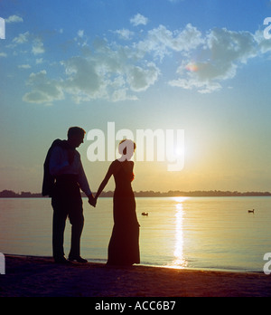 young couple walking on beach at sunset Stock Photo