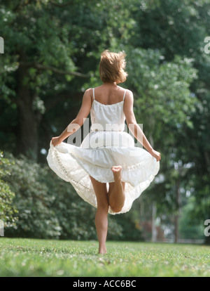 carefree young woman runs barefoot in a park Stock Photo