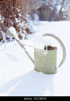A watering can in a garden covered in snow. Stock Photo