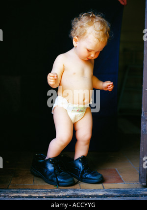 A girl trying on big shoes. Stock Photo