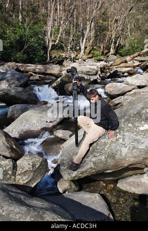 Young Outdoor Photographer Carrying Camera on Tripod and Negotiating Boulders Beside Stream Great Smoky Mountains National Park Stock Photo