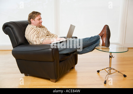Man using a laptop in armchair Stock Photo