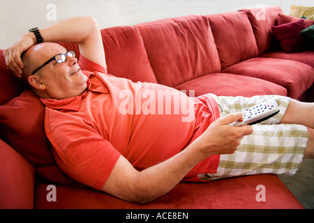 Man watching television on sofa Stock Photo