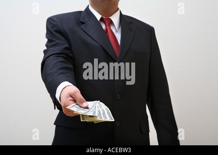 Businessman holding out handful of money Stock Photo