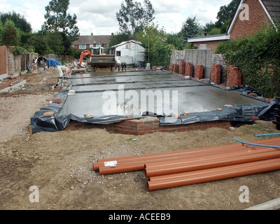 Labourer & work in progress on recently delivered wet ready mix concrete pour to substructure floor slab  to new house under construction England UK Stock Photo