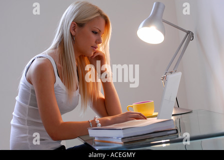 young female sitting at desk using laptop computer Stock Photo