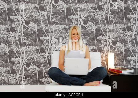 young female sitting on chair using laptop computer Stock Photo