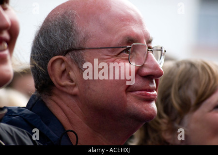 Man with bald head and eye glasses smiling while  watching a music concert Stock Photo