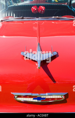 Front of a red Chevrolet Bel Air convertible classic car with emblem hood ornament and fuzzy dice hanging in the windshield Stock Photo