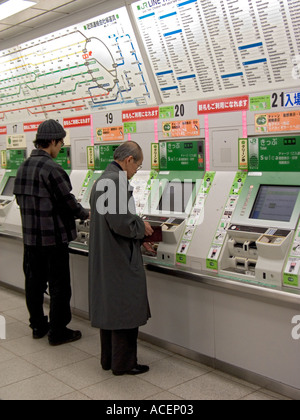 Commuters purchasing train tickets from automated vending machines in Tokyo Station Stock Photo