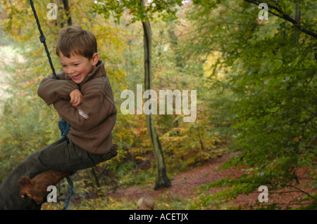 boy swinging on rope in wood Stock Photo