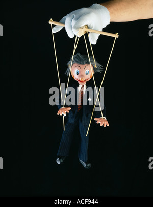 Businessman in a suit puppet being operated by a puppeteer Stock Photo