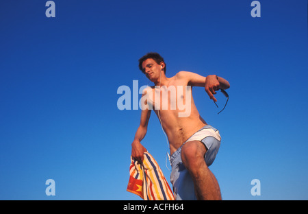 Tall, thin young German man balancing on a post listening to music