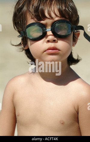 Toddler  looks curiously wearing swim goggles at beach Model Released Stock Photo
